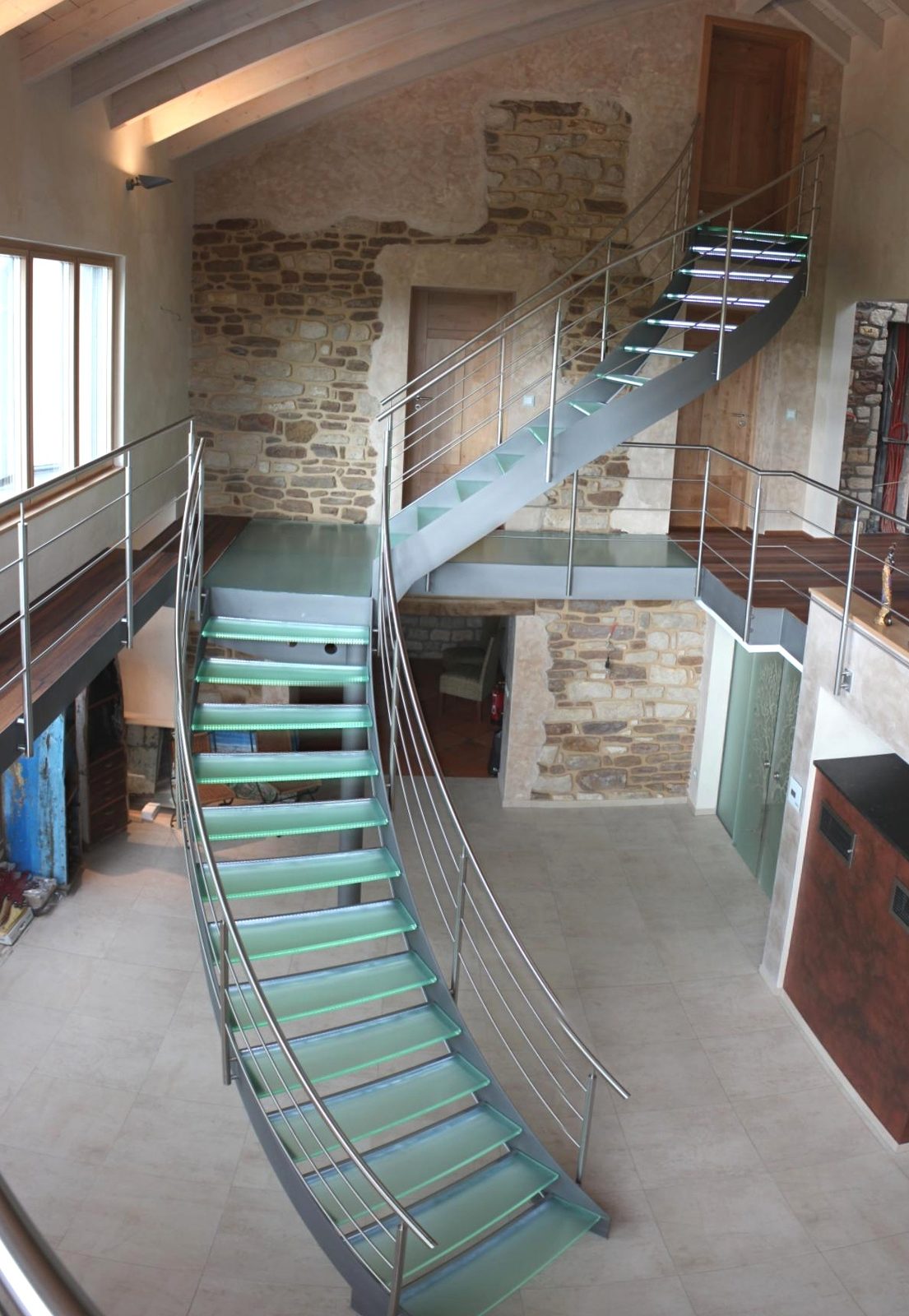 Innentreppe mit Glasstufen und Edelstahlgeländer an einer Natursteinwand – AN Metallbau GmbH