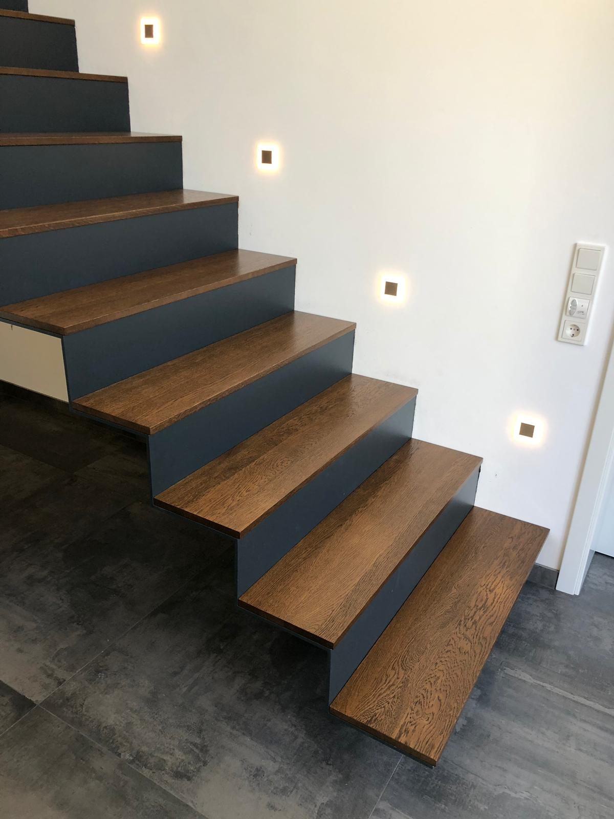 Freitragende Holztreppe mit dunklen Stufen und schlankem Stahlgeländer – AN Metallbau GmbH