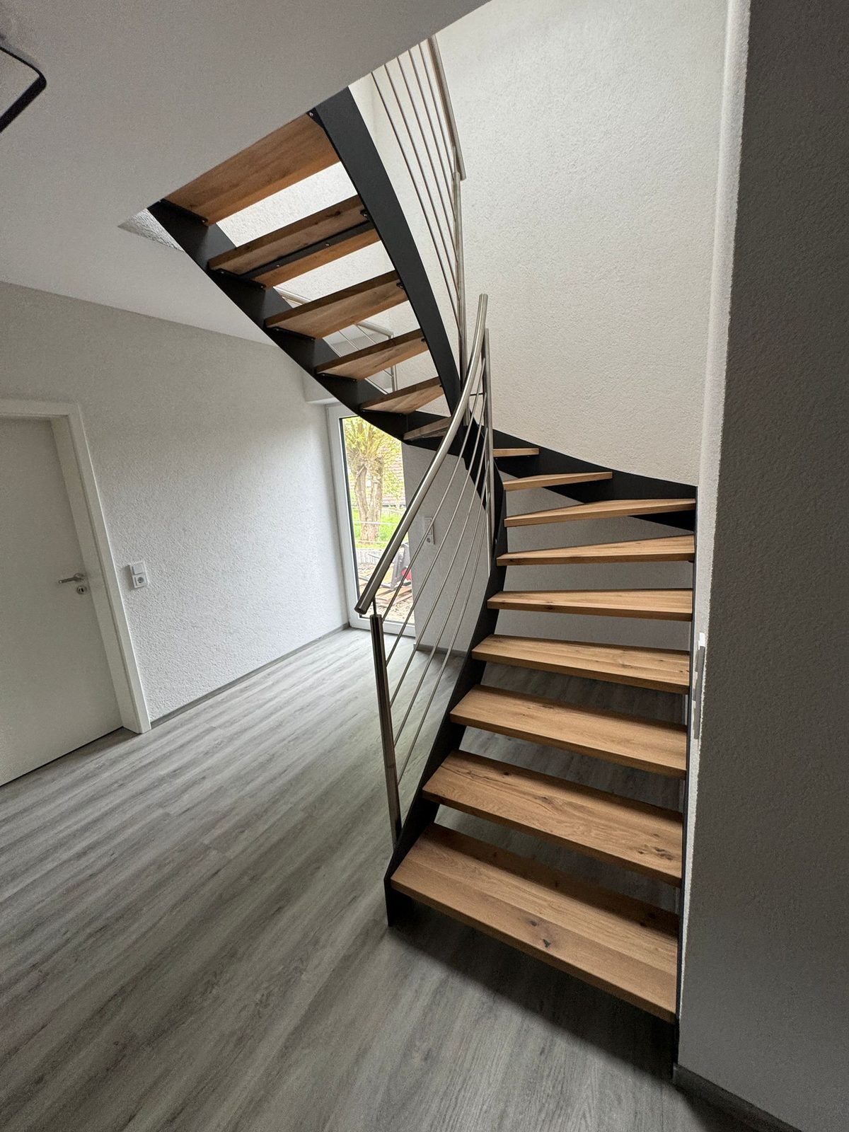 Elegante gewendelte Holztreppe mit Stahlwange – AN Metallbau GmbH