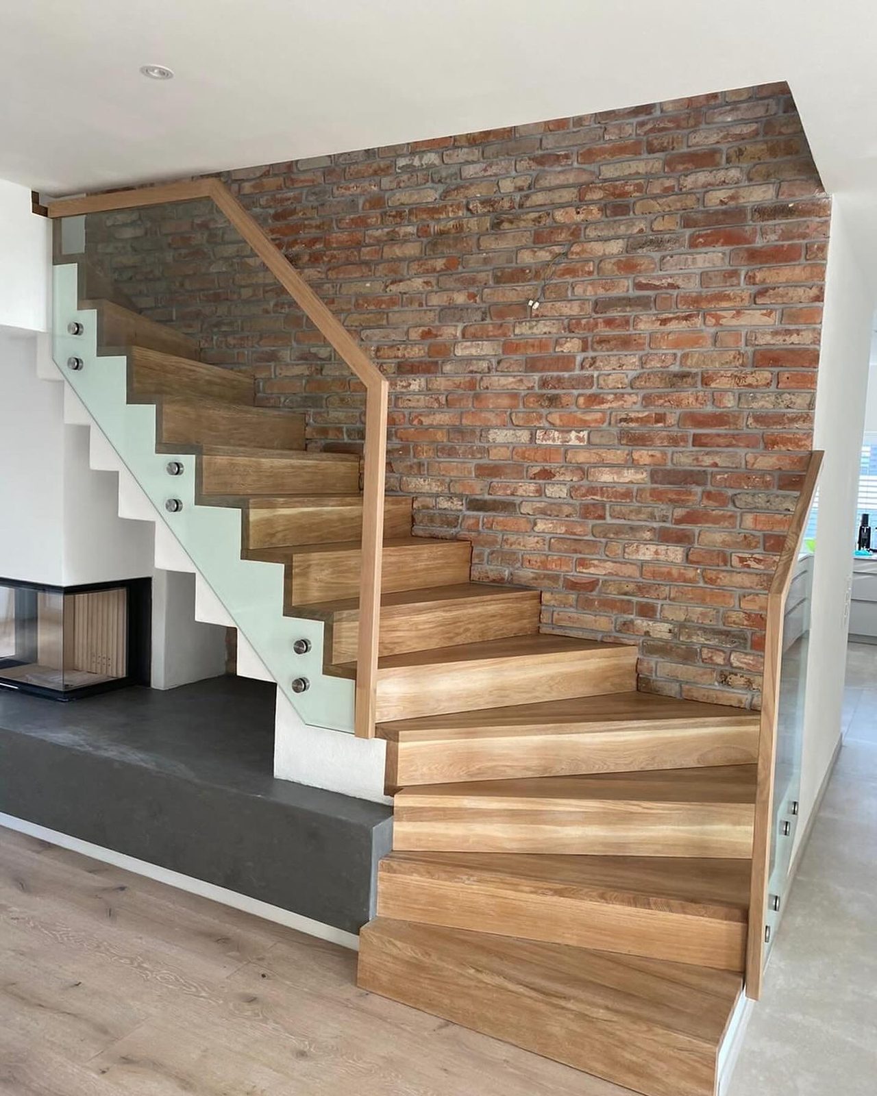 Innentreppe mit Holzstufen vor einer Natursteinwand – AN Metallbau GmbH